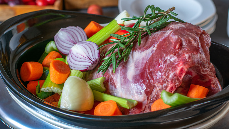 Carne y verduras crudas en una olla de cocción lenta.