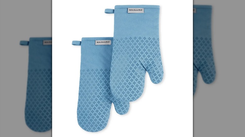 Un par de guantes de horno KitchenAid Asteroid Silicone Grip de terciopelo azul claro/azul sobre un fondo blanco