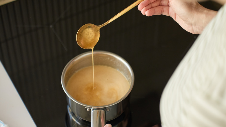 Una cuchara de caramelo que se cocina a mano en una cacerola de aluminio