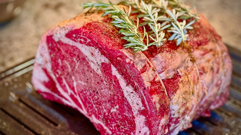 Asado de costilla cruda atado con condimentos en una hoja de metal para cocinar