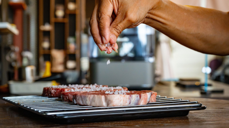 Mano espolvoreando sal gruesa sobre el filete