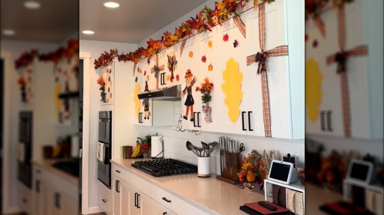 Una cocina blanca decorada con hojas de otoño y una guirnalda de hojas de arce.