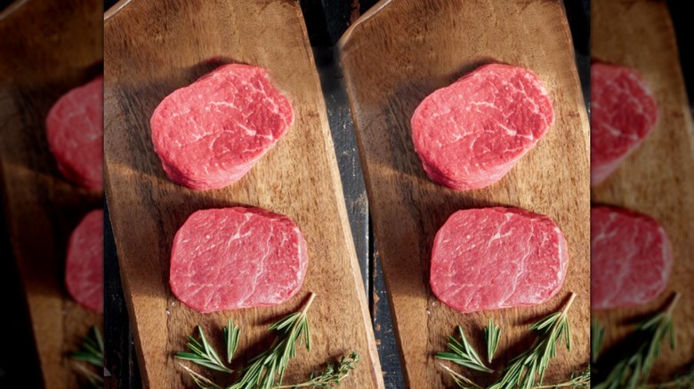 Cuatro filetes de filet mignon crudos sobre dos tablas de cortar de madera